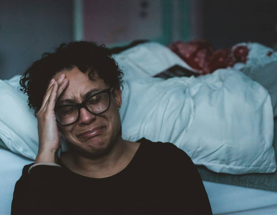 woman crying on the side of a bed