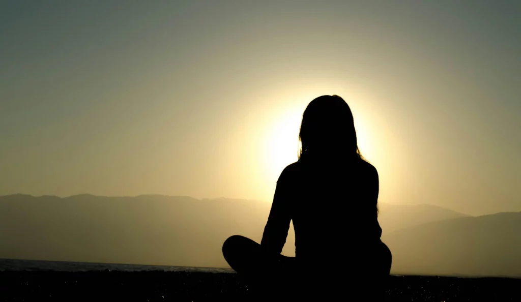 Person meditating while watching a sunset
